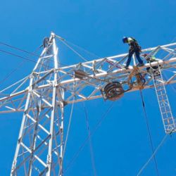 Obrero sobre torre eléctrica haciendo el montaje